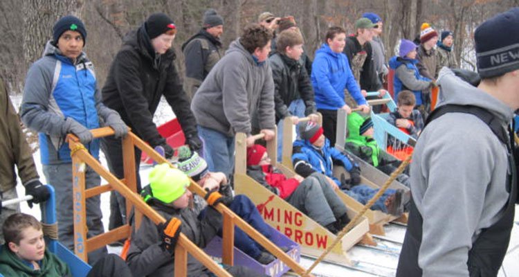 A large group of Scouts, one pusher and one rider per sled, in a lineup preparing to race