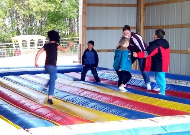 Several youth jumping on a inflatable bounce pad