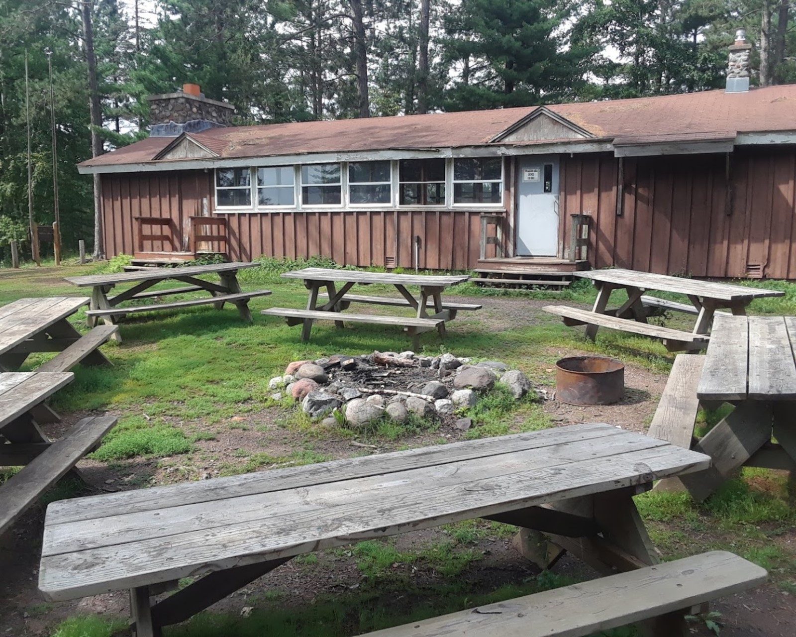 A ring of picnic tables with a long one-story building in the background