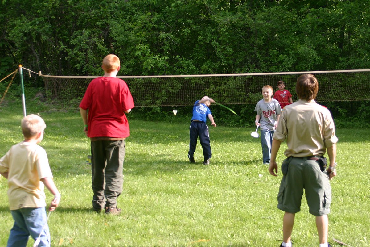 3 Scouts on each side of a badminton net playing