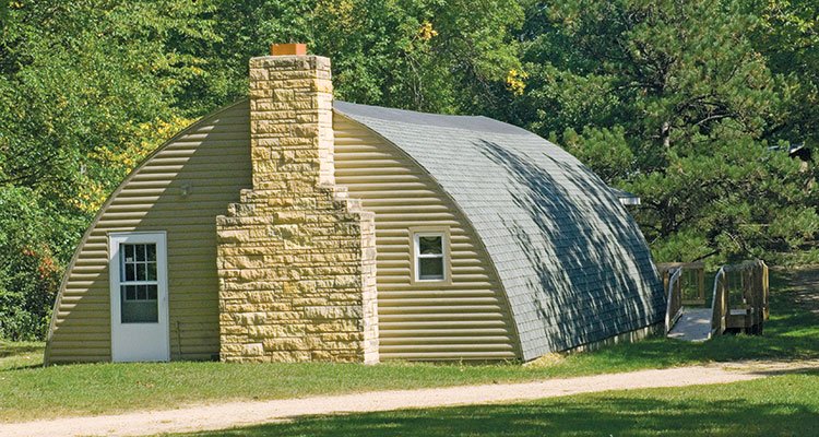 A large building with a steep curved roof near the road