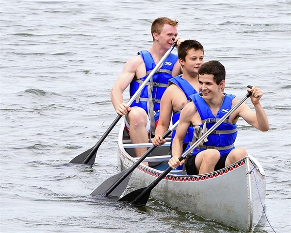 A group of three young men canoeing