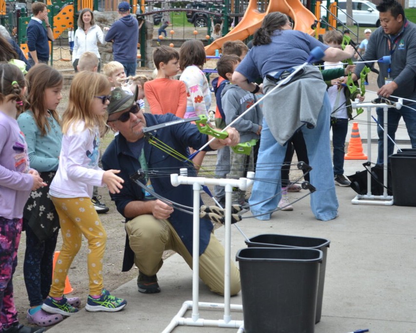 Three instructors leading a group of 1st and 2nd graders in foam archery