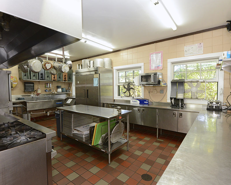 A large commercial kitchen with a large stainless steel island and countertops going around the entire room
