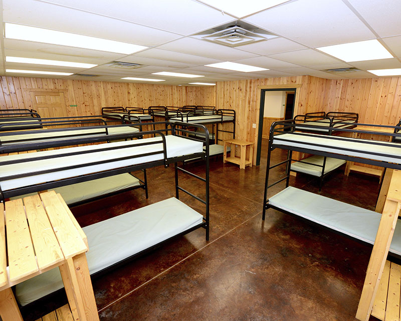 A bunkroom with 9 bunkbeds in view, spaced out such that all are usable