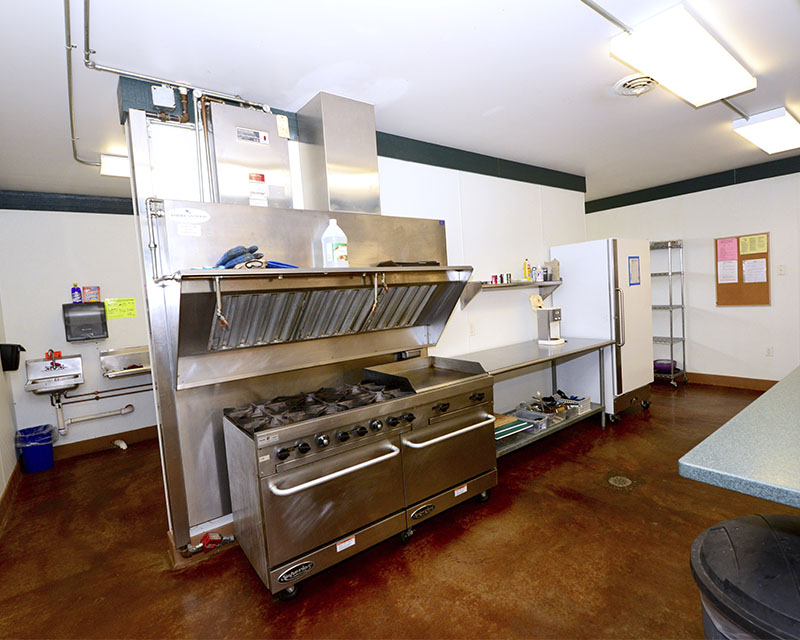 A kitchen with two commercial stove/ovens and several countertops in view